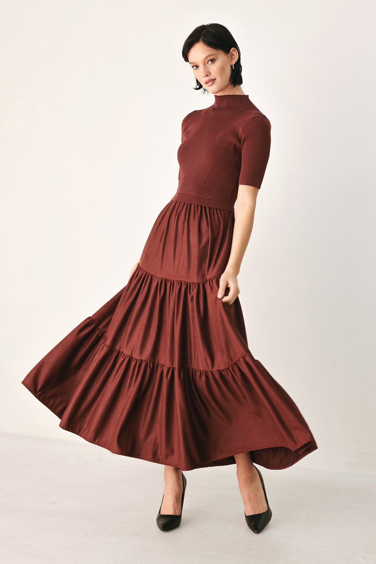 A woman modeling a rust-brown tiered midi dress with short sleeves and a mock neck | FREEMARKET