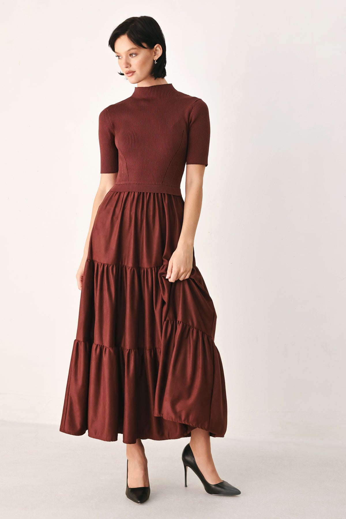 A woman modeling a rust-brown tiered midi dress with short sleeves and a mock neck | FREEMARKET