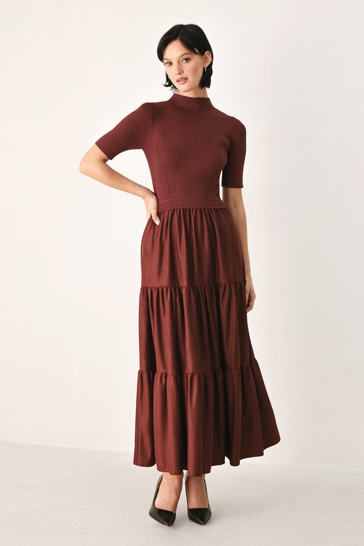 A woman modeling a rust-brown tiered midi dress with short sleeves and a mock neck | FREEMARKET