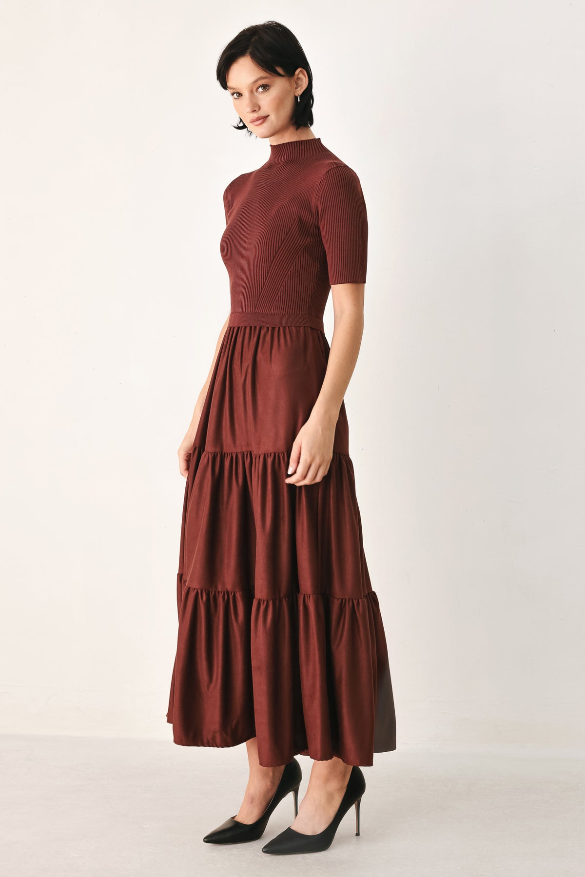 A woman modeling a rust-brown tiered midi dress with short sleeves and a mock neck | FREEMARKET