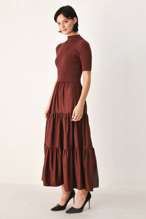 A woman modeling a rust-brown tiered midi dress with short sleeves and a mock neck | FREEMARKET