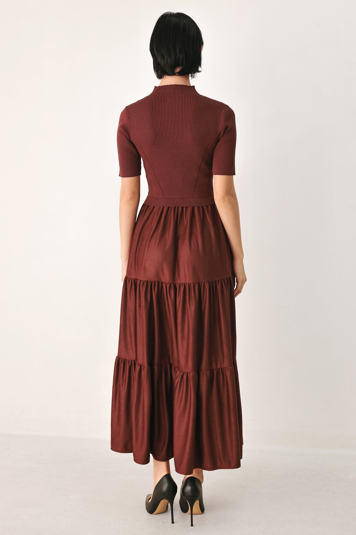 A woman modeling a rust-brown tiered midi dress with short sleeves and a mock neck | FREEMARKET