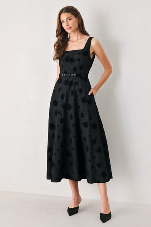 Woman wearing a sleeveless, square neckline black midid dress with jacquard floral pattern and slim waist belt | FREEMARKET 