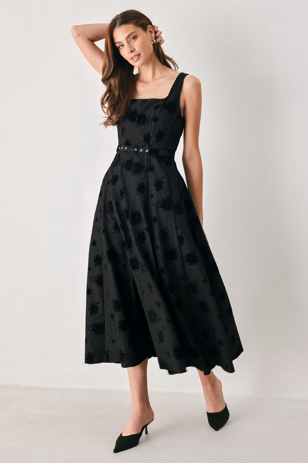Woman wearing a sleeveless, square neckline black midid dress with jacquard floral pattern and slim waist belt | FREEMARKET 