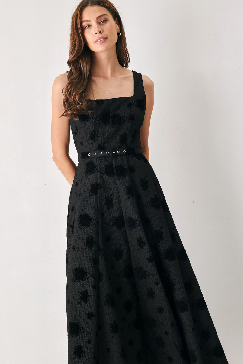 Woman wearing a sleeveless, square neckline black midid dress with jacquard floral pattern and slim waist belt | FREEMARKET 