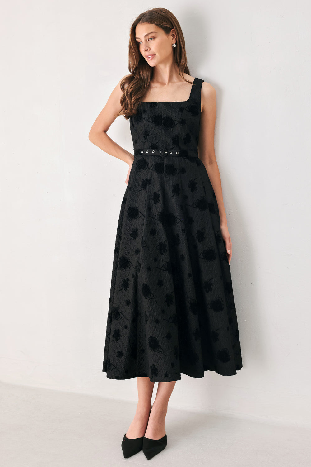 Woman wearing a sleeveless, square neckline black midid dress with jacquard floral pattern and slim waist belt | FREEMARKET 
