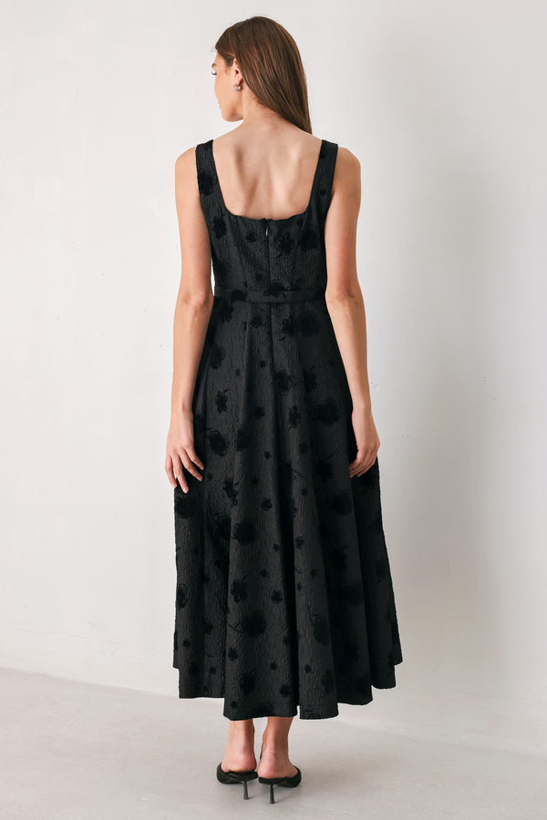 Woman wearing a sleeveless, square neckline black midid dress with jacquard floral pattern and slim waist belt | FREEMARKET 