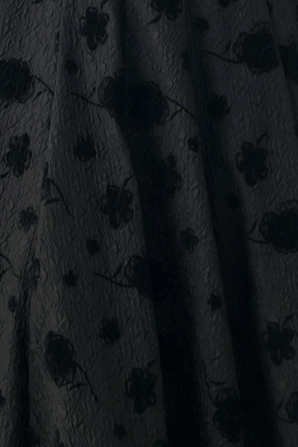 Woman wearing a sleeveless, square neckline black midid dress with jacquard floral pattern and slim waist belt | FREEMARKET 