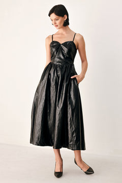 A woman modeling a black faux leather midi dress with a shiny, textured finish, featuring thin spaghetti straps, a sweetheart neckline, a gathered corset-style bodice, and a flared skirt | FREEMARKET