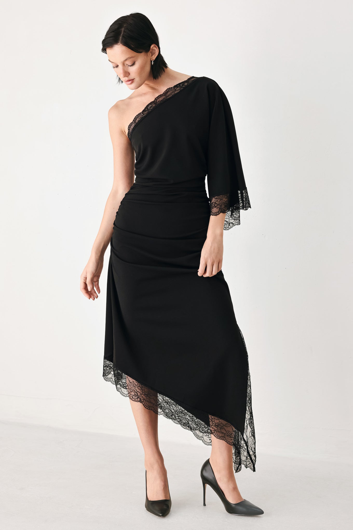 A model wearing a black one-shoulder midi dress with lace trim on the sleeve and hem | FREEMARKET