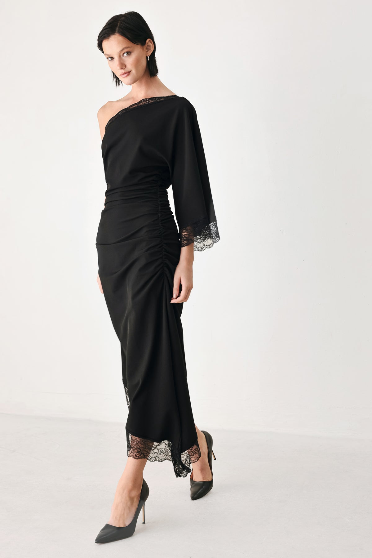 A model wearing a black one-shoulder midi dress with lace trim on the sleeve and hem | FREEMARKET