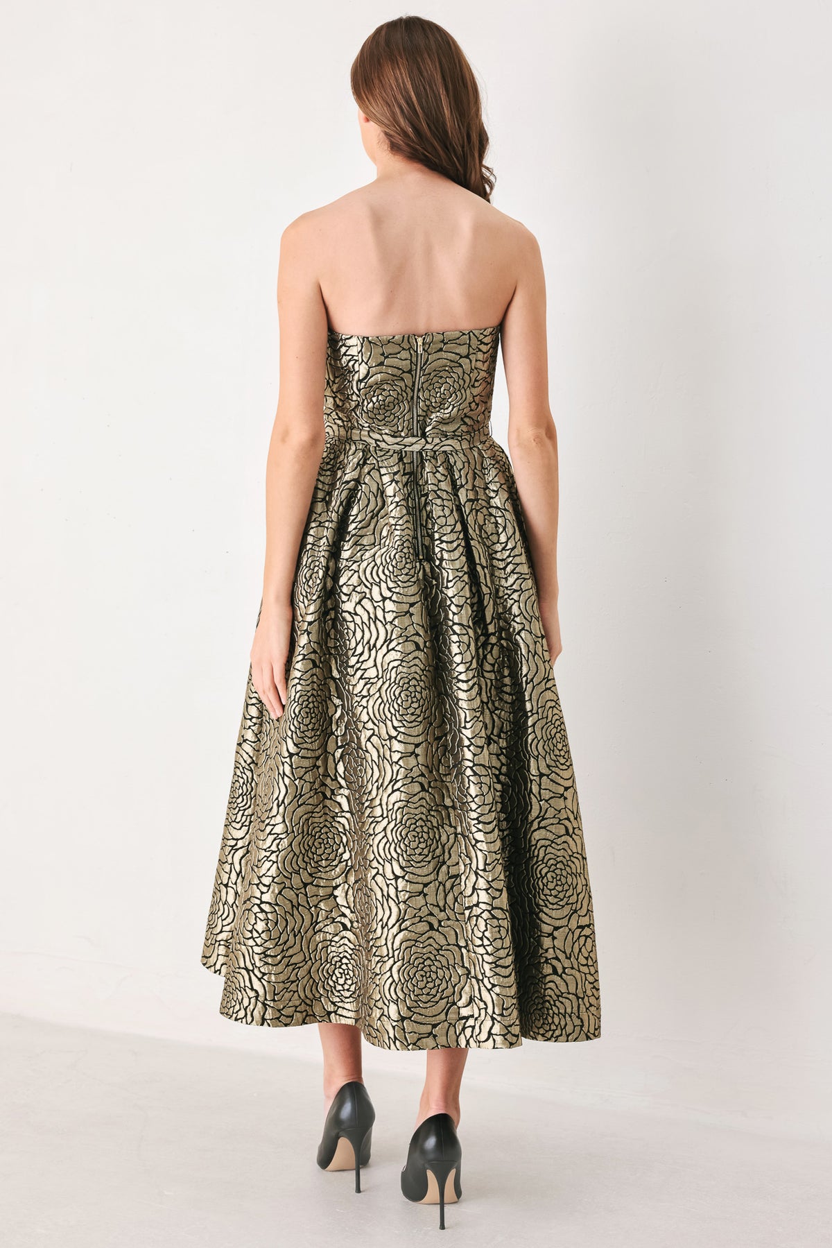 A woman models a strapless midi dress with a black and metallic gold floral pattern | FREEMARKET