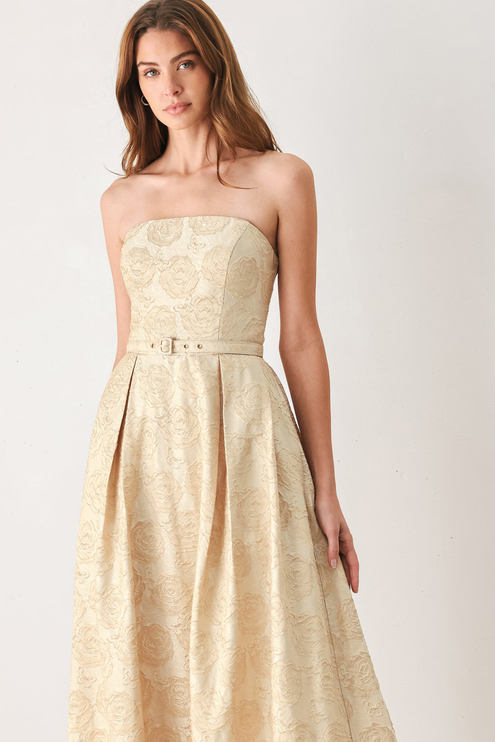 Woman wearing a strapless gold jacquard floral midi dress with a matching waist belt | FREEMARKET