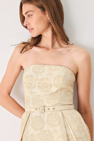 Woman wearing a strapless gold jacquard floral midi dress with a matching waist belt | FREEMARKET