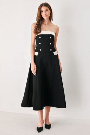 Woman wearing a strapless black midi dress with cream strap across the strapless neckline, double breasted buttons, faux pockets | FREEMARKET