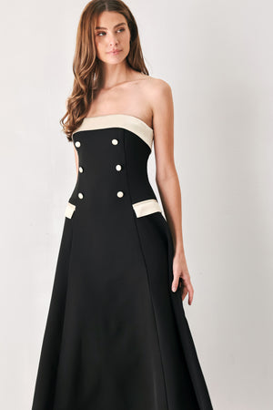 Woman wearing a strapless black midi dress with cream strap across the strapless neckline, double breasted buttons, faux pockets | FREEMARKET