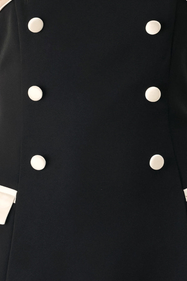 Woman wearing a strapless black midi dress with cream strap across the strapless neckline, double breasted buttons, faux pockets | FREEMARKET