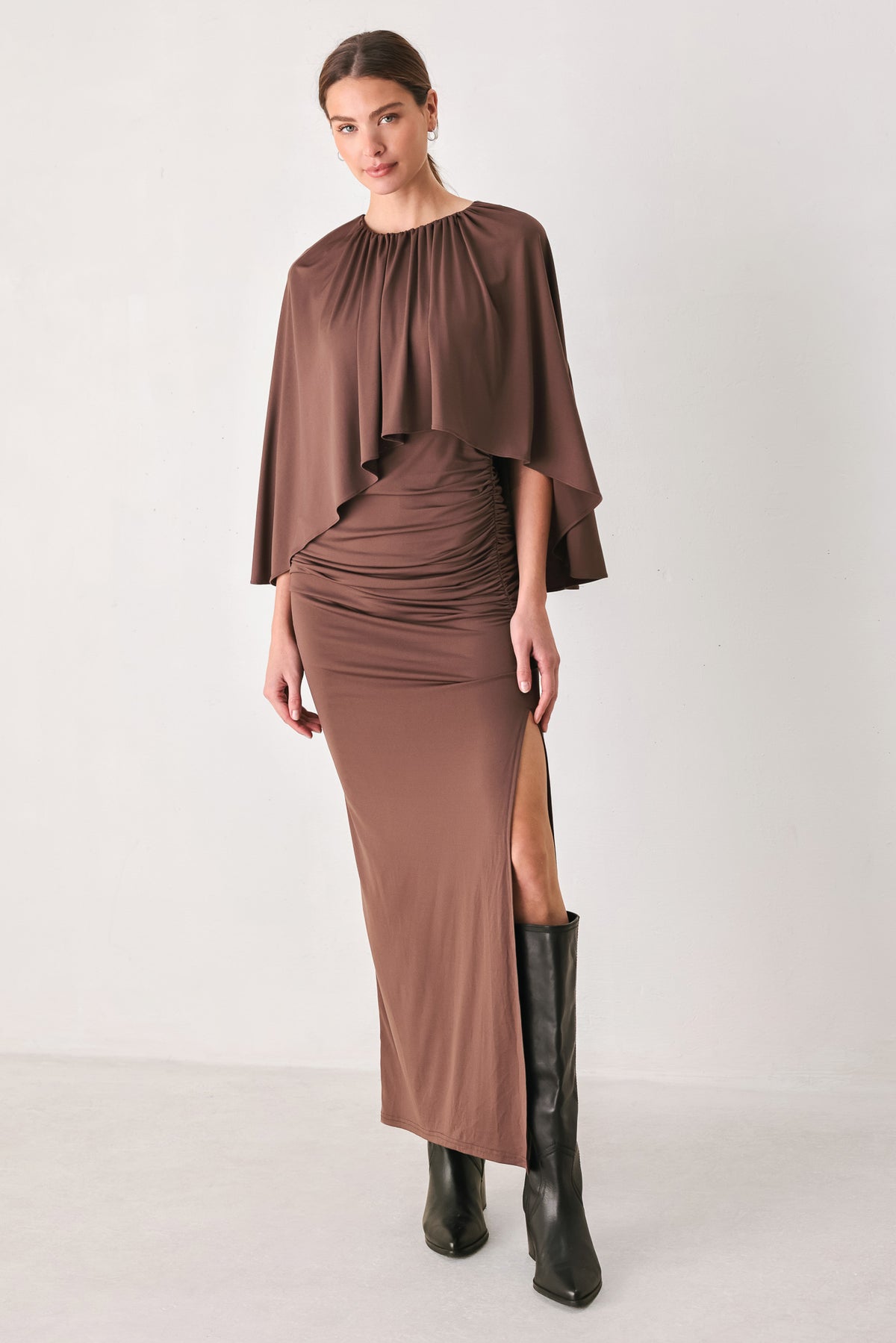 A woman models a brown mauve draped midi dress with a high neck, wide cape sleeves, ruched detailing at the waist, and a side slit | FREEMARKET