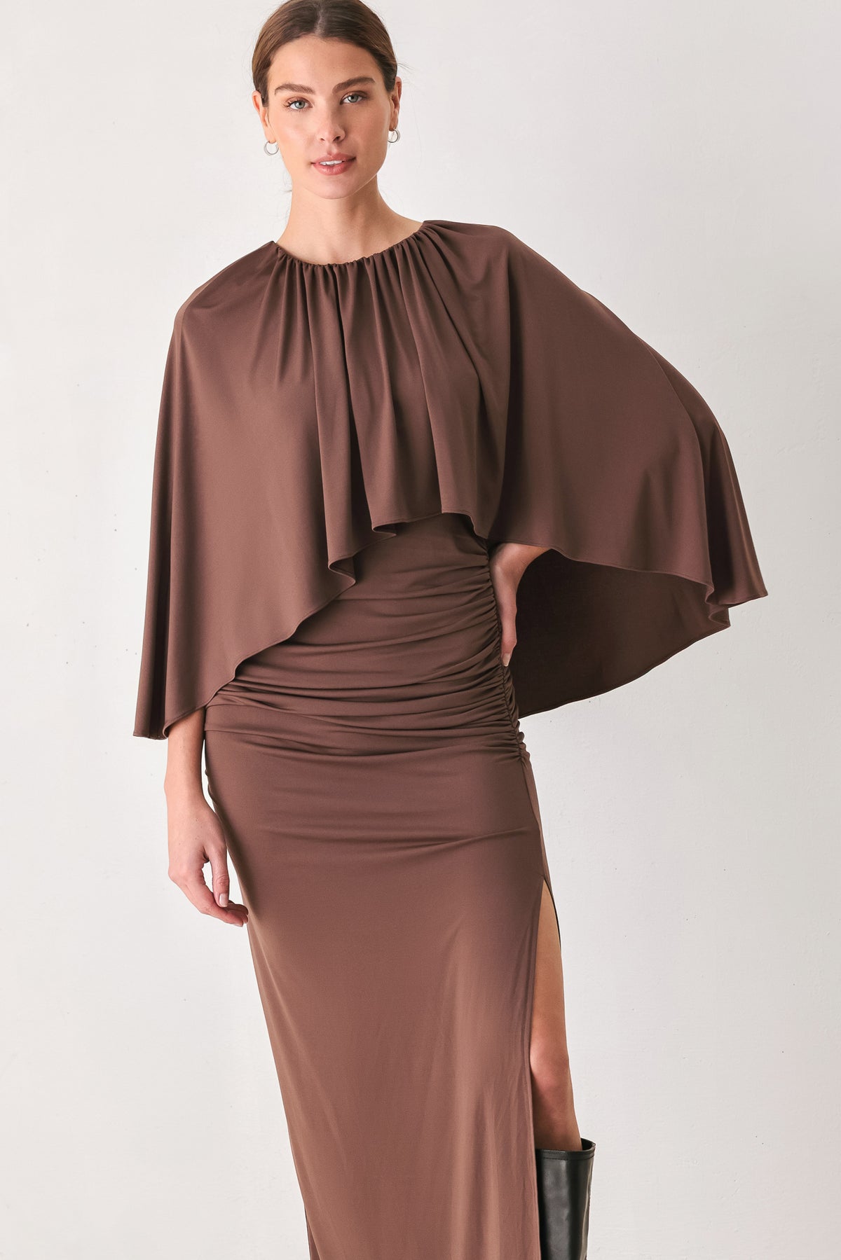 A woman models a brown mauve draped midi dress with a high neck, wide cape sleeves, ruched detailing at the waist, and a side slit | FREEMARKET