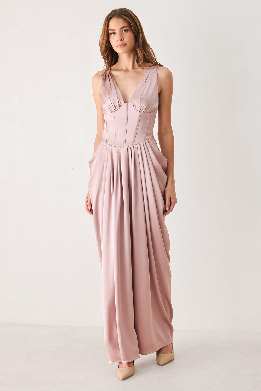 Woman wearing a pink satin sleeveless gown with structured boning on around the waist and pleated skirt | FREEMARKET