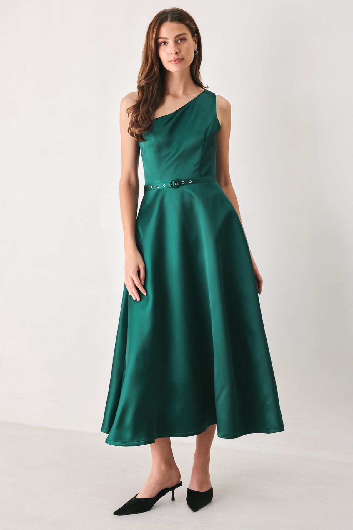 A woman models a sleeveless one-shoulder midi dress in emerald green satin, featuring a structured bodice, a thin waist belt, and a flared skirt | FREEMARKET