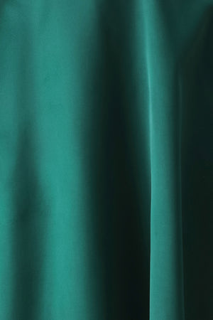 A woman models a sleeveless one-shoulder midi dress in emerald green satin, featuring a structured bodice, a thin waist belt, and a flared skirt | FREEMARKET