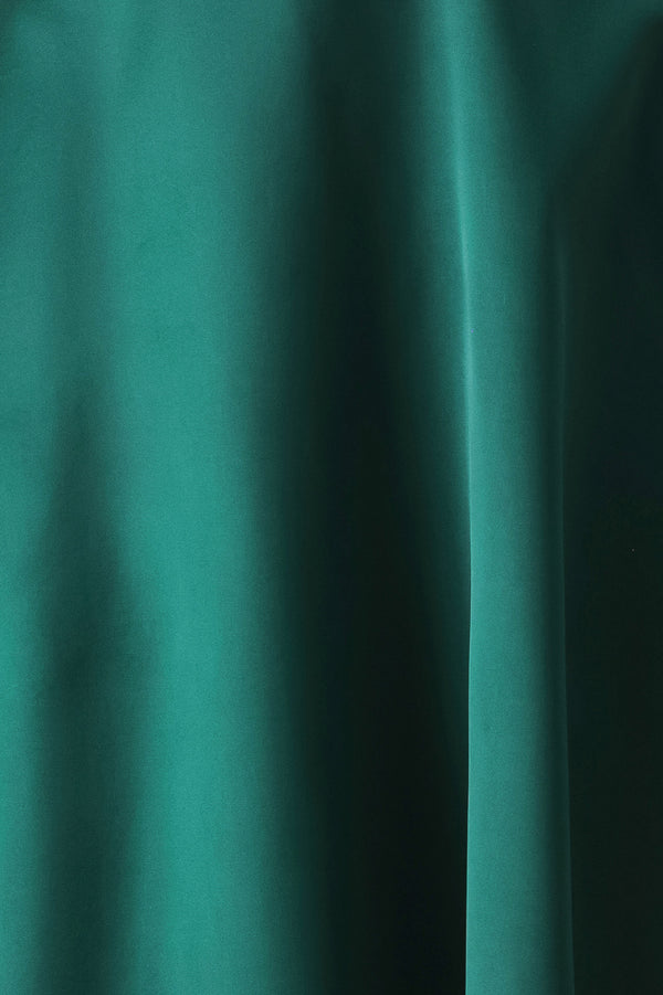 A woman models a sleeveless one-shoulder midi dress in emerald green satin, featuring a structured bodice, a thin waist belt, and a flared skirt | FREEMARKET