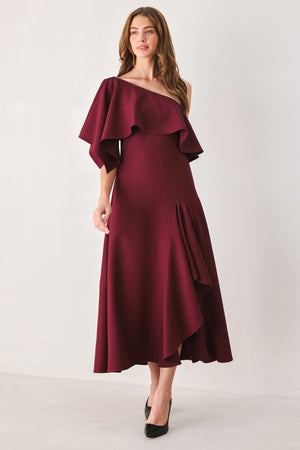 Woman wearing a burgundy midi dress with with an asymmetrical neckline with a large ruffle and a ruffle along the leg slit | FREEMARKET