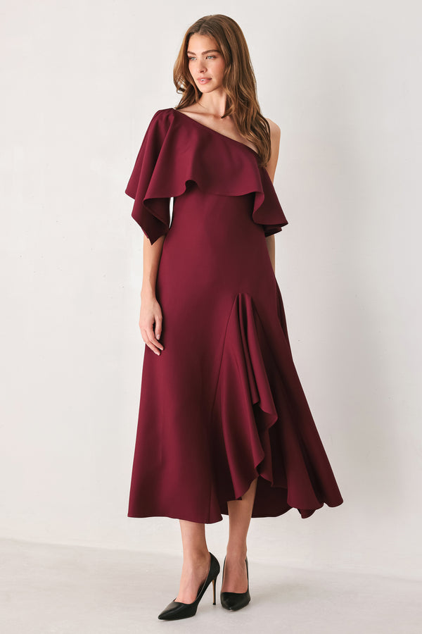 Woman wearing a burgundy midi dress with with an asymmetrical neckline with a large ruffle and a ruffle along the leg slit | FREEMARKET