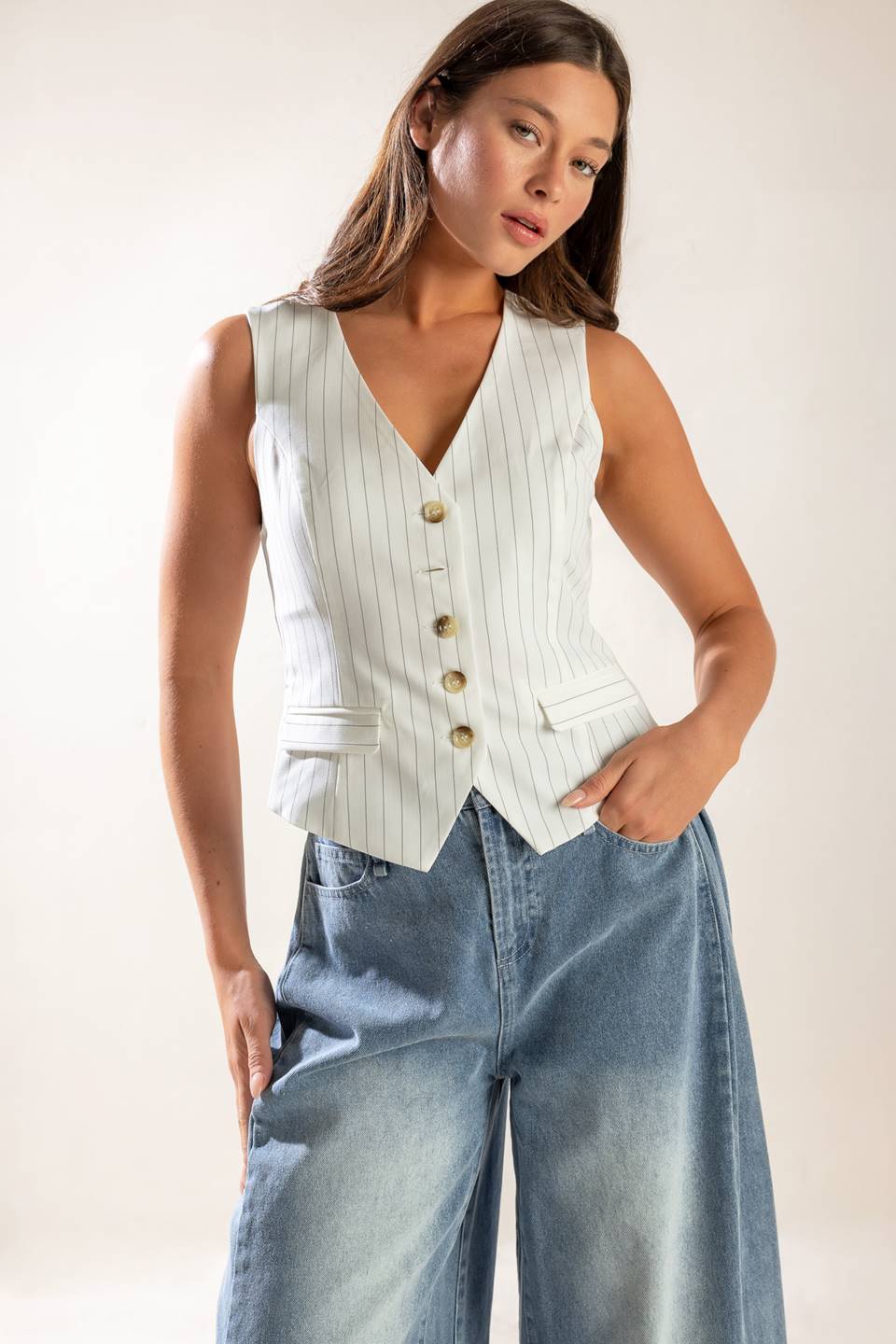 A striped woven vest featuring V neckline, button down, sleeveless and solid back with button detail. 