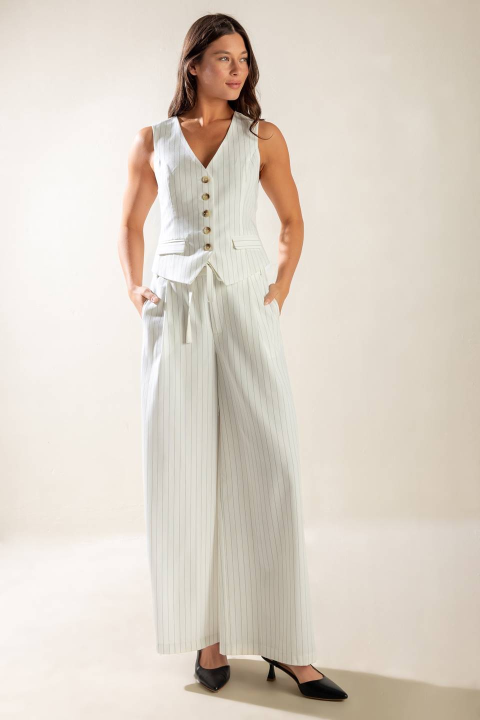 A striped woven vest featuring V neckline, button down, sleeveless and solid back with button detail. 