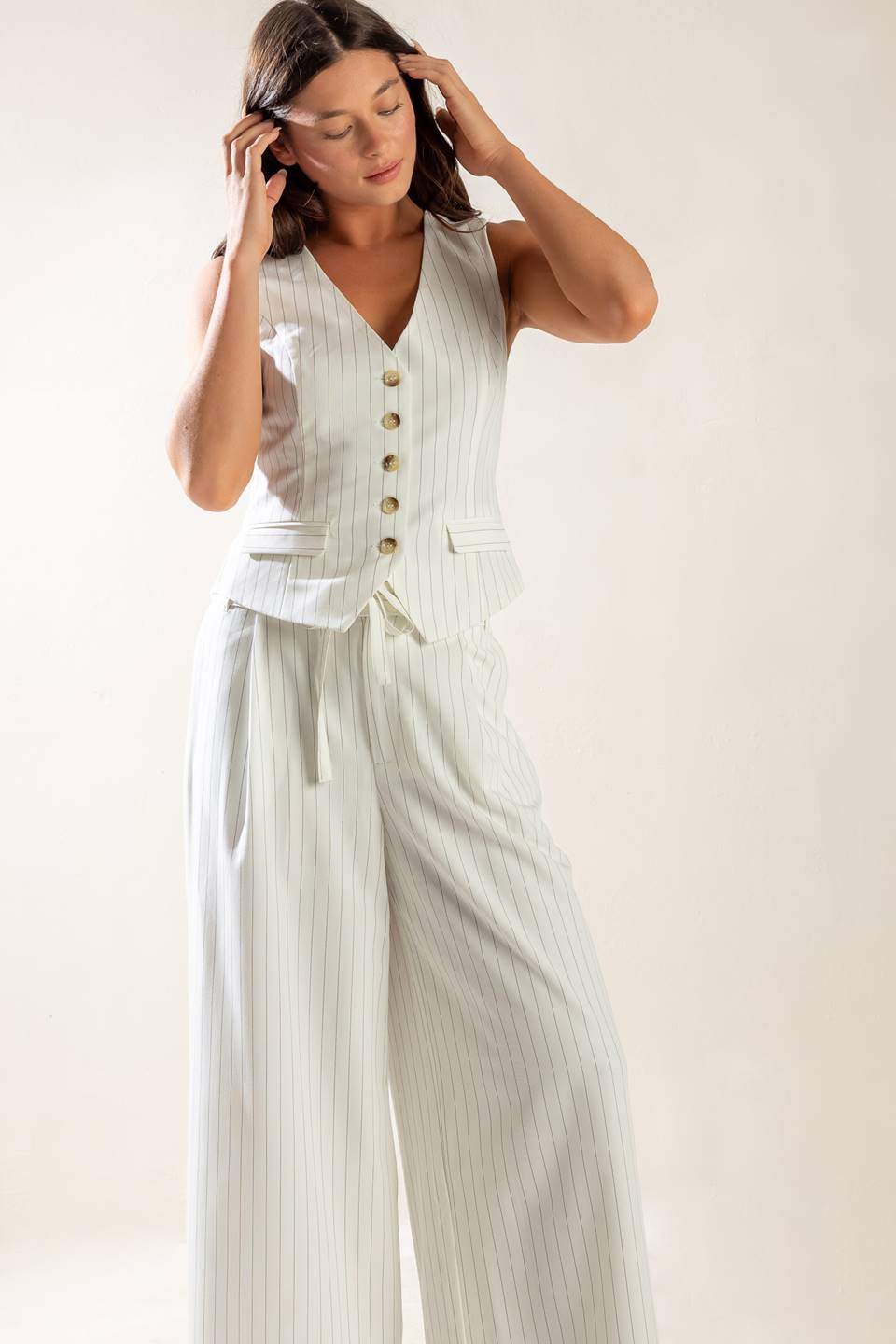 A striped woven vest featuring V neckline, button down, sleeveless and solid back with button detail. 