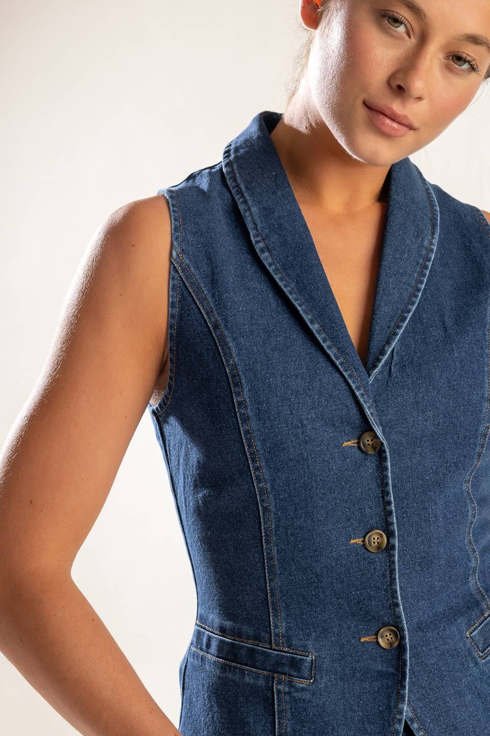 A washed denim vest featuring shawl collar, sleeveless and button down.