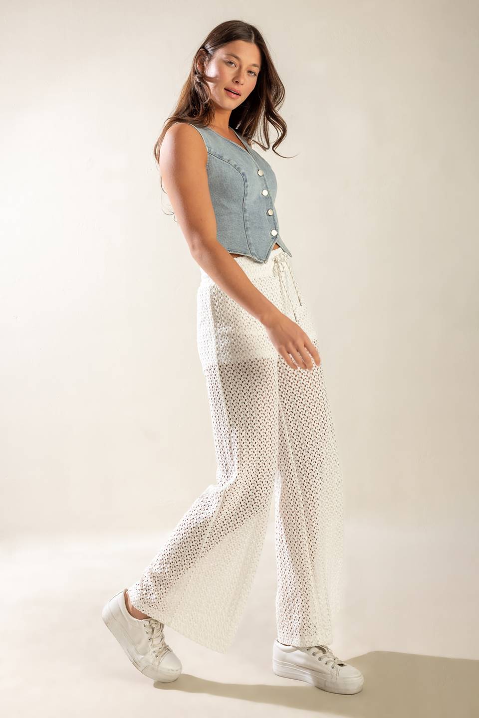 A cropped, light washed, sleeveless, denim vest with front button closure.