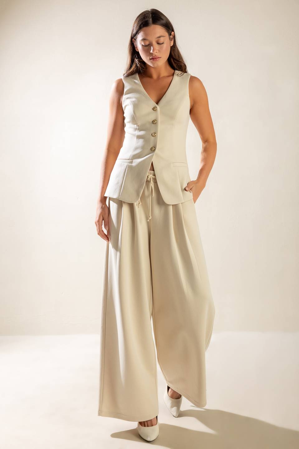 A sleeveless solid woven vest featuring V neckline, button down and back slit.