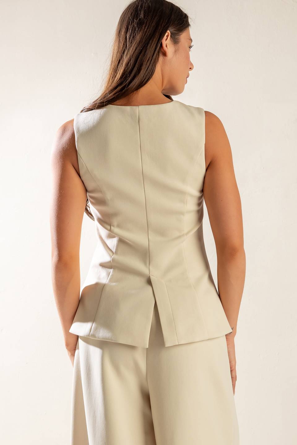 A sleeveless solid woven vest featuring V neckline, button down and back slit.