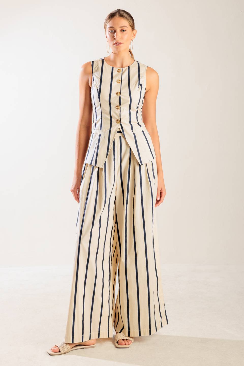 A striped woven vest featuring round neckline, sleeveless and button down.