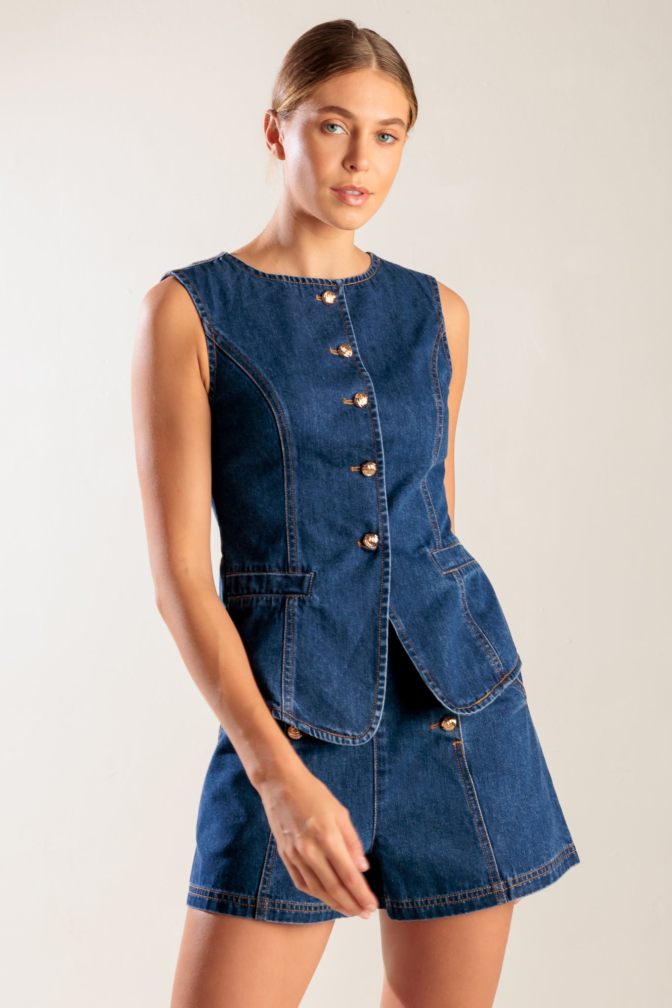 A denim vest featuring round neckline, sleeveless and front button closure.