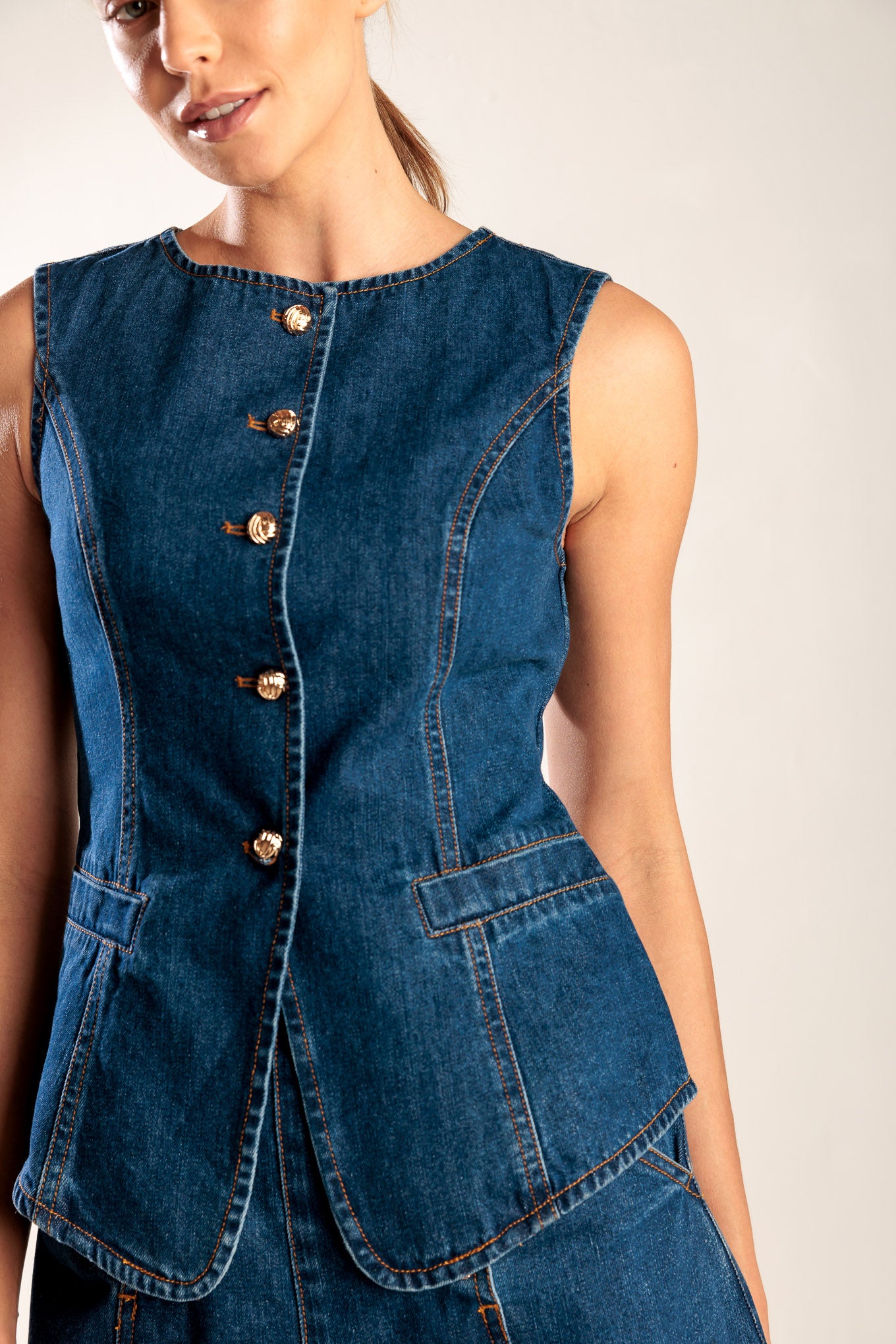 A denim vest featuring round neckline, sleeveless and front button closure.