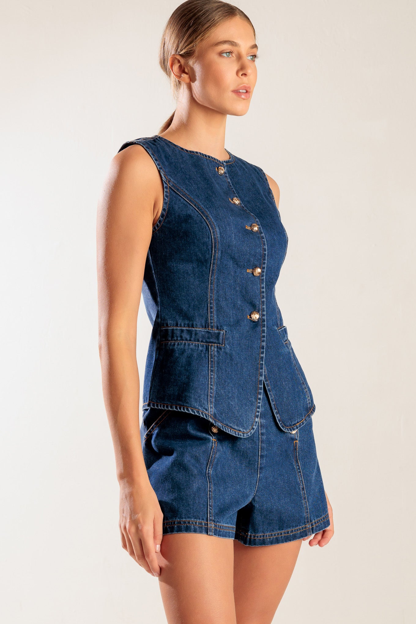 A denim vest featuring round neckline, sleeveless and front button closure.