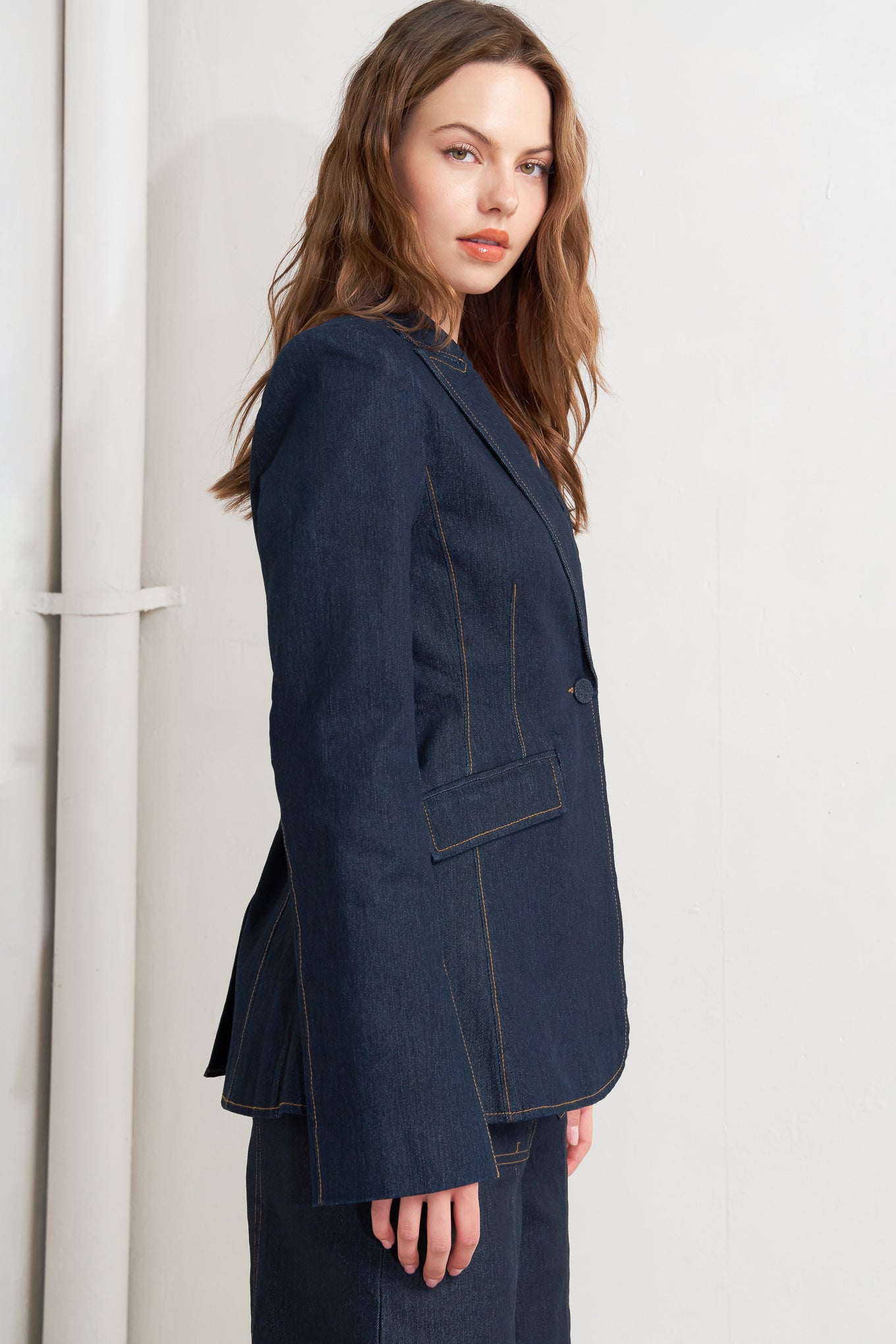 A denim blazer with single button closure and slit at sleeve