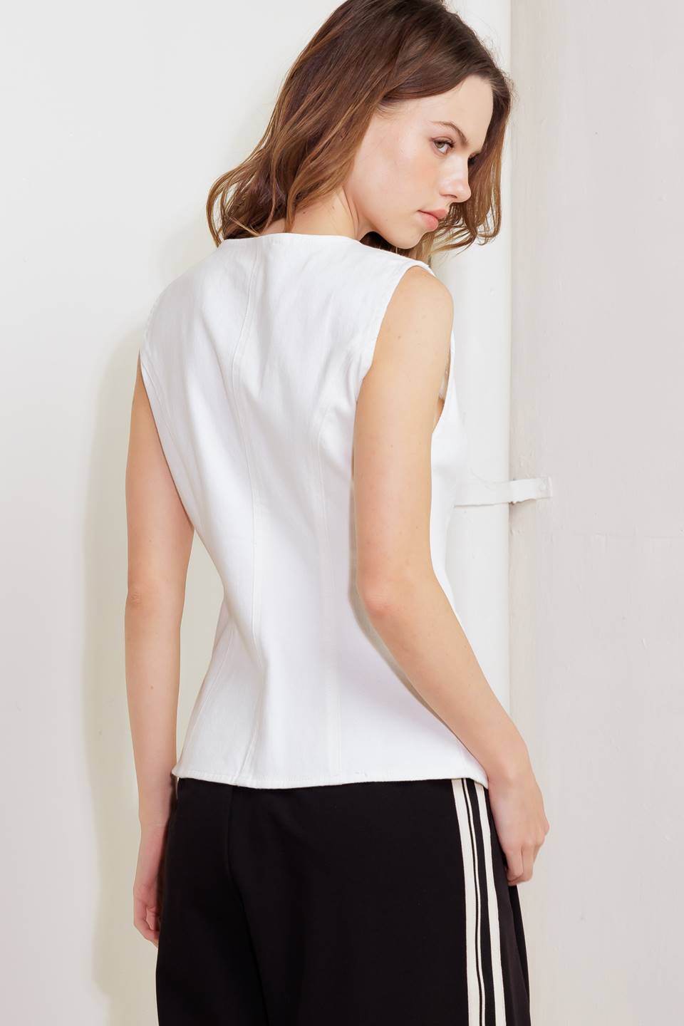 A solid white woven vest featuring V neckline, sleeveless and front button closure