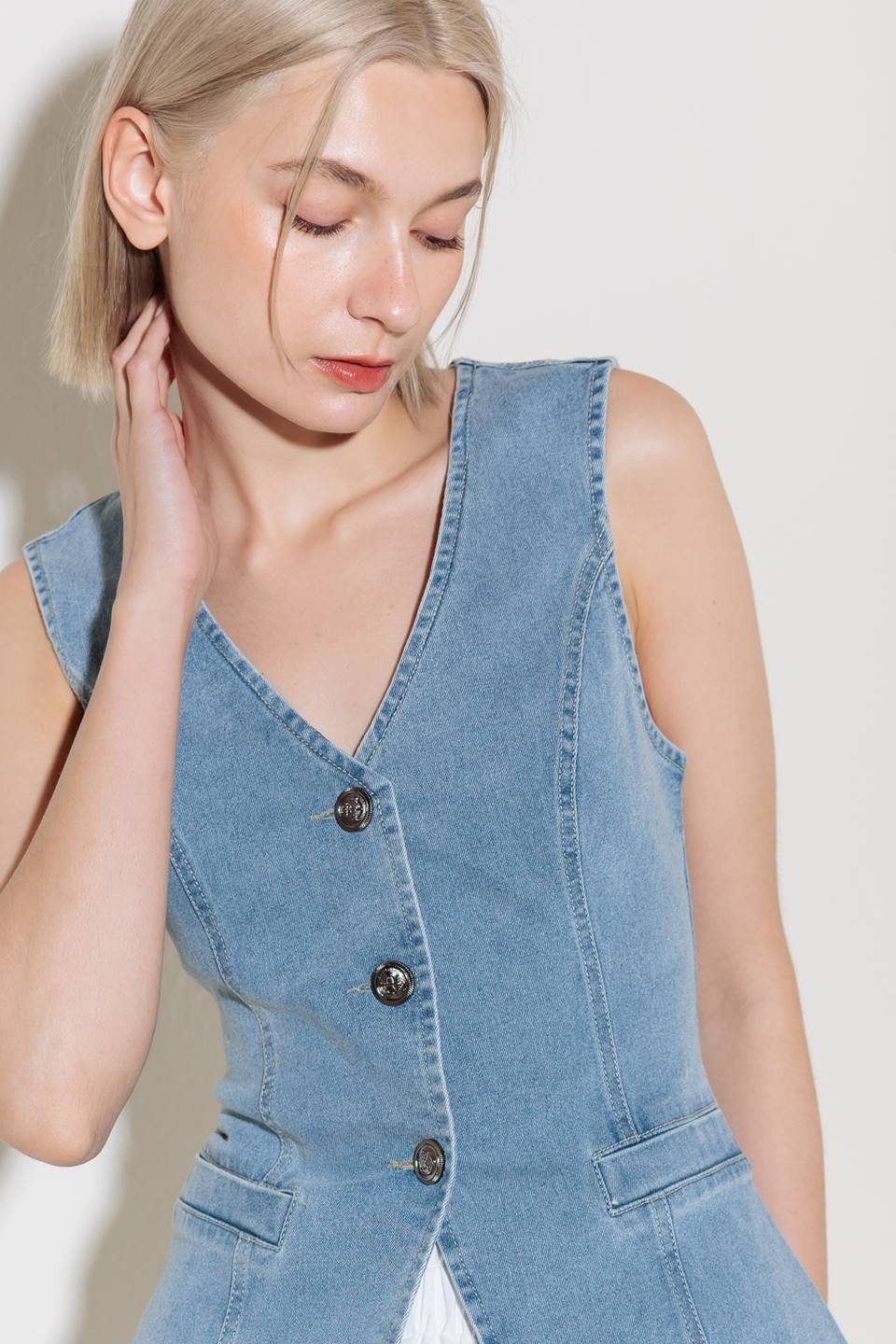 A washed denim vest with V neckline and front closure.
