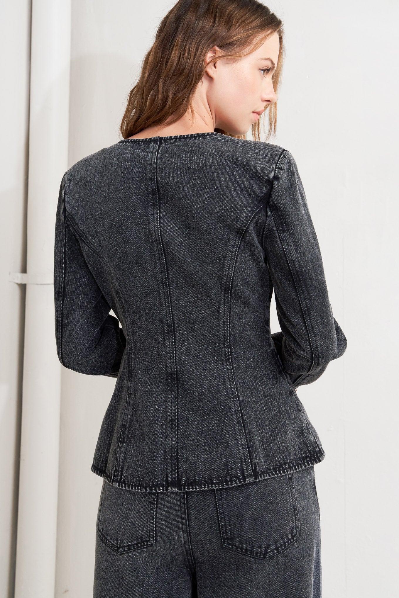 A washed denim jacket featuring round neckline and front button closure with pockets.