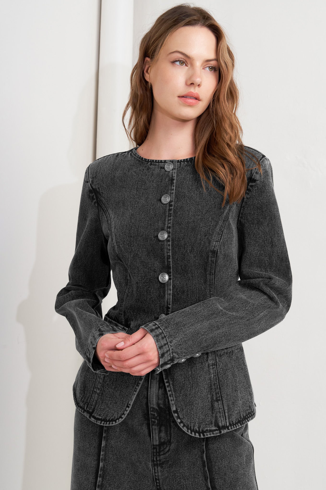 A washed denim jacket featuring round neckline and front button closure with pockets.