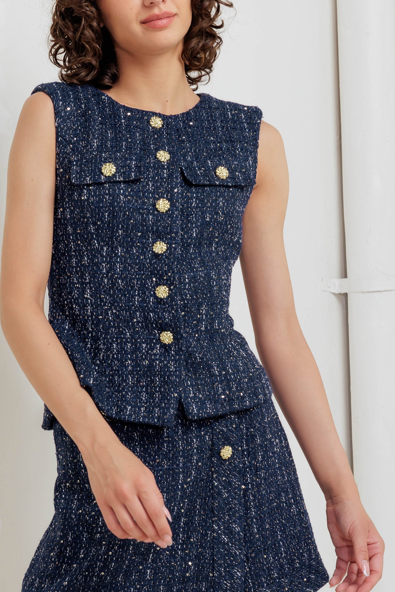 A woven tweed vest featuring round neckline, sleeveless and front button down closure
