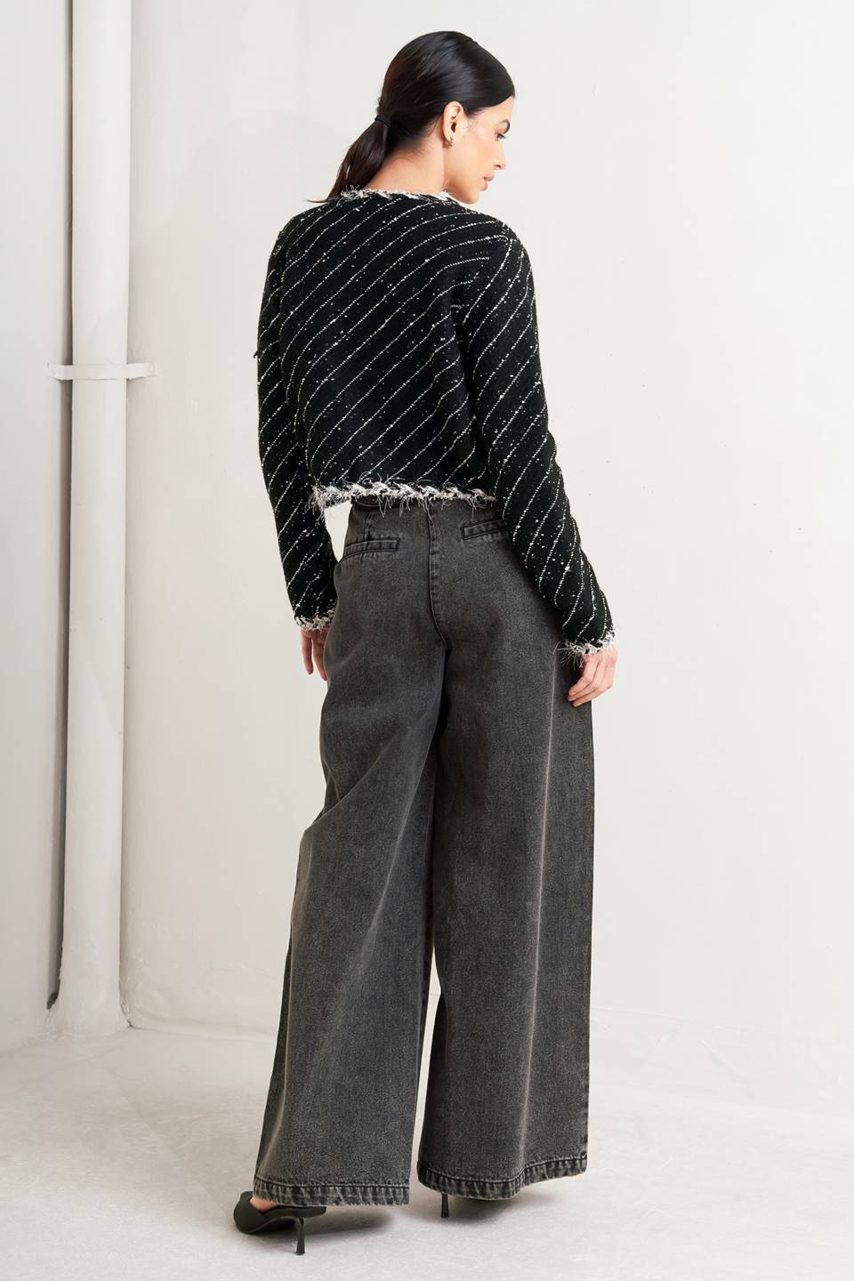 Woman wearing a black and white patterned jacket and wide-leg jeans on a white background, A sweater knit cropped jacket featuring round neckline, contrasting edge and front hook &amp; eye closure - FLYING TOMATO