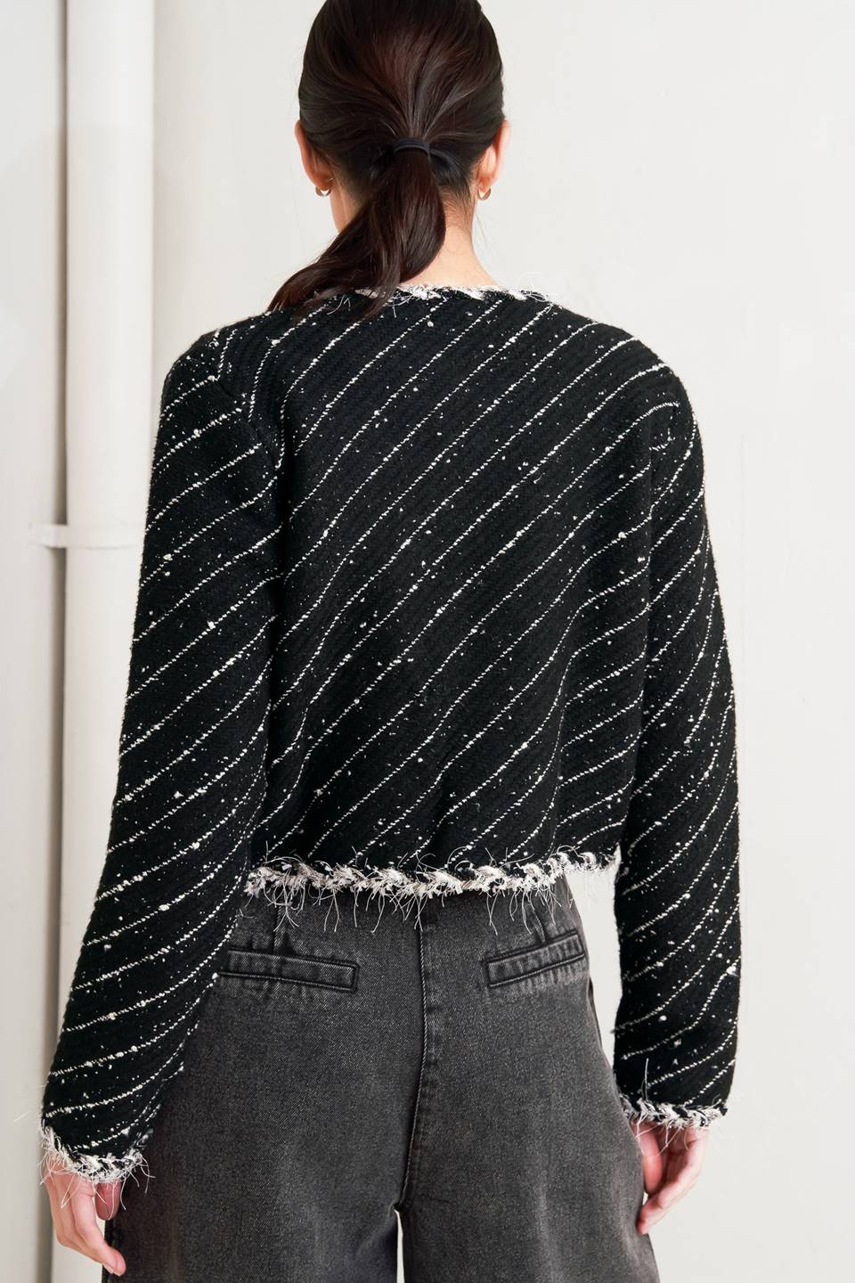 Woman wearing a black and white patterned jacket and wide-leg jeans on a white background, A sweater knit cropped jacket featuring round neckline, contrasting edge and front hook &amp; eye closure - FLYING TOMATO