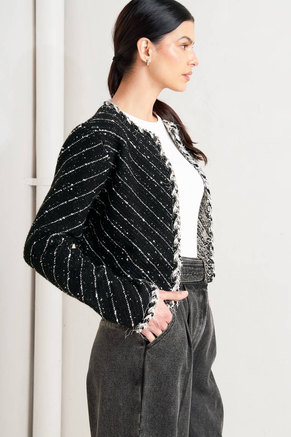 Woman wearing a black and white patterned jacket and wide-leg jeans on a white background, A sweater knit cropped jacket featuring round neckline, contrasting edge and front hook &amp; eye closure - FLYING TOMATO