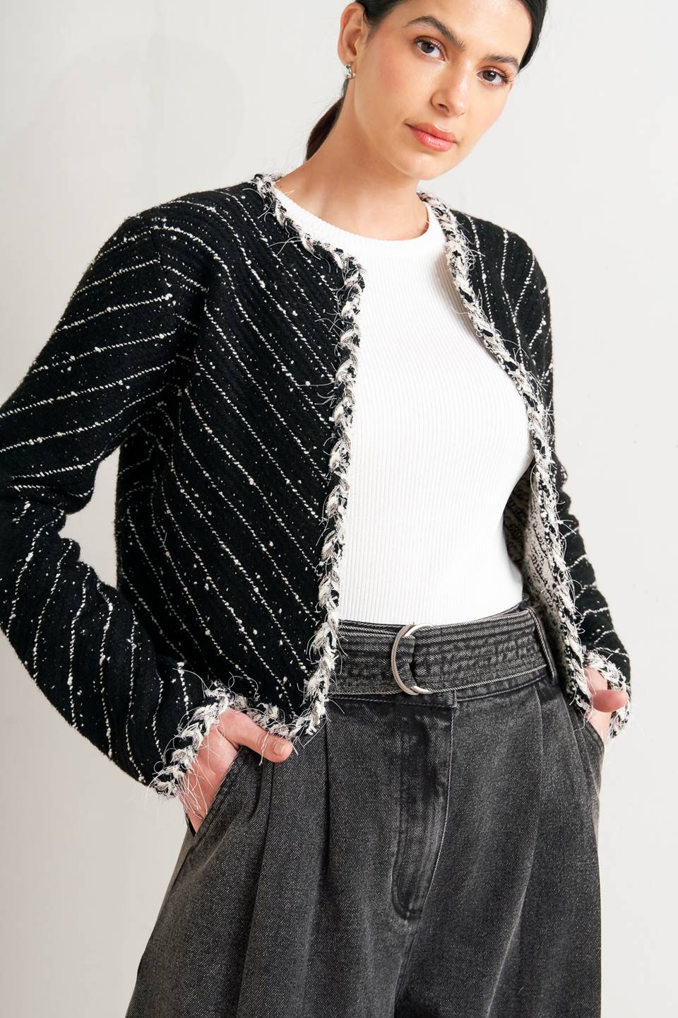Woman wearing a black and white patterned jacket and wide-leg jeans on a white background, A sweater knit cropped jacket featuring round neckline, contrasting edge and front hook &amp; eye closure - FLYING TOMATO